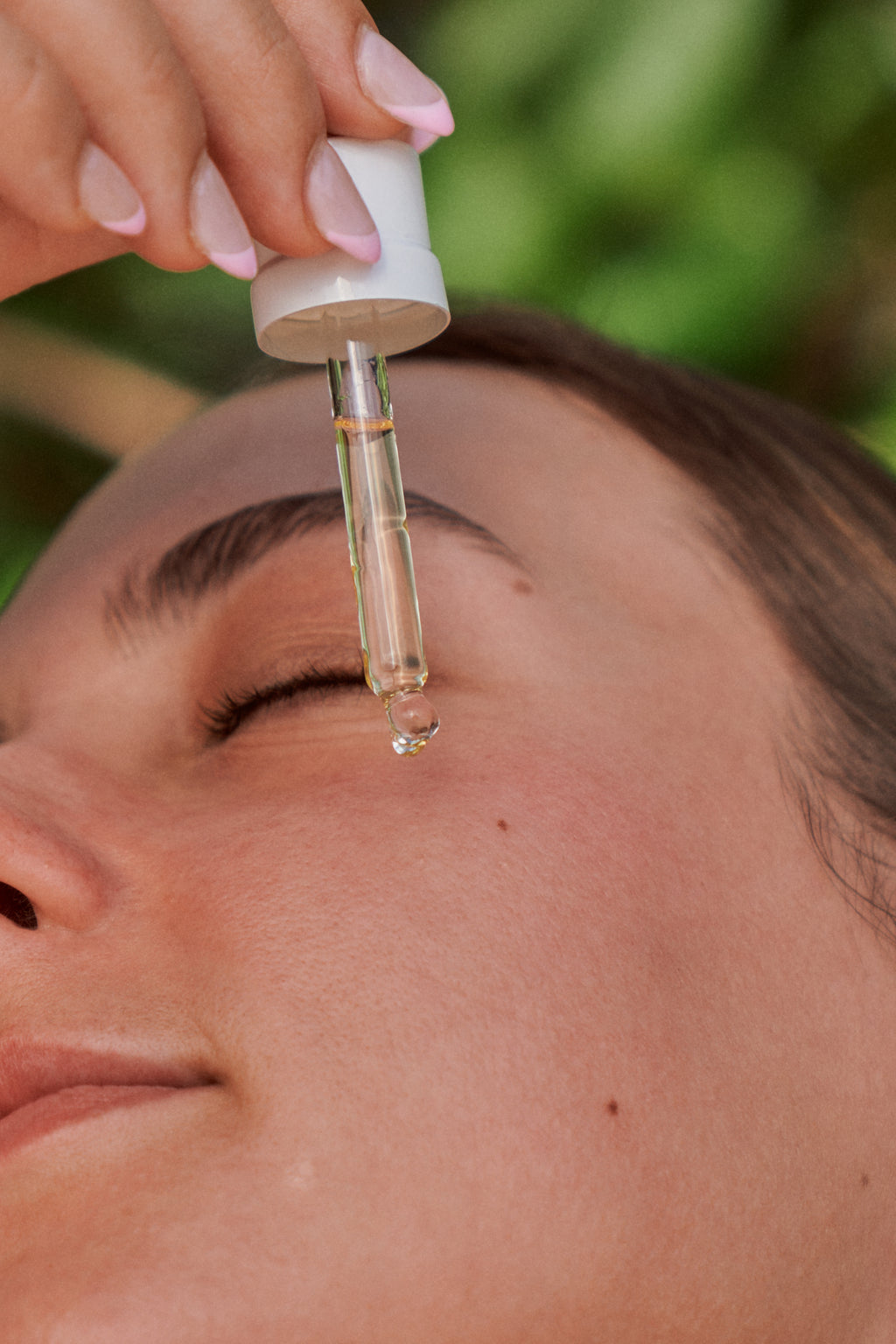 Close-up of a dropper applying face oil to skin