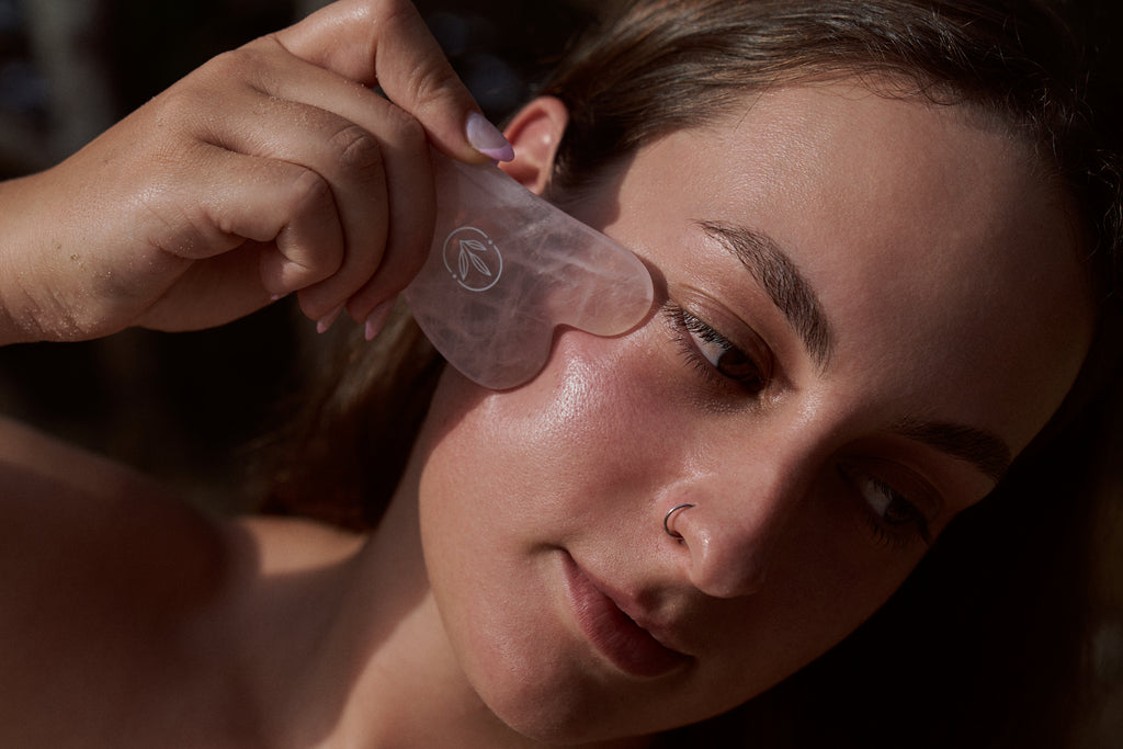 Using a rose quartz gua sha tool on the cheek
