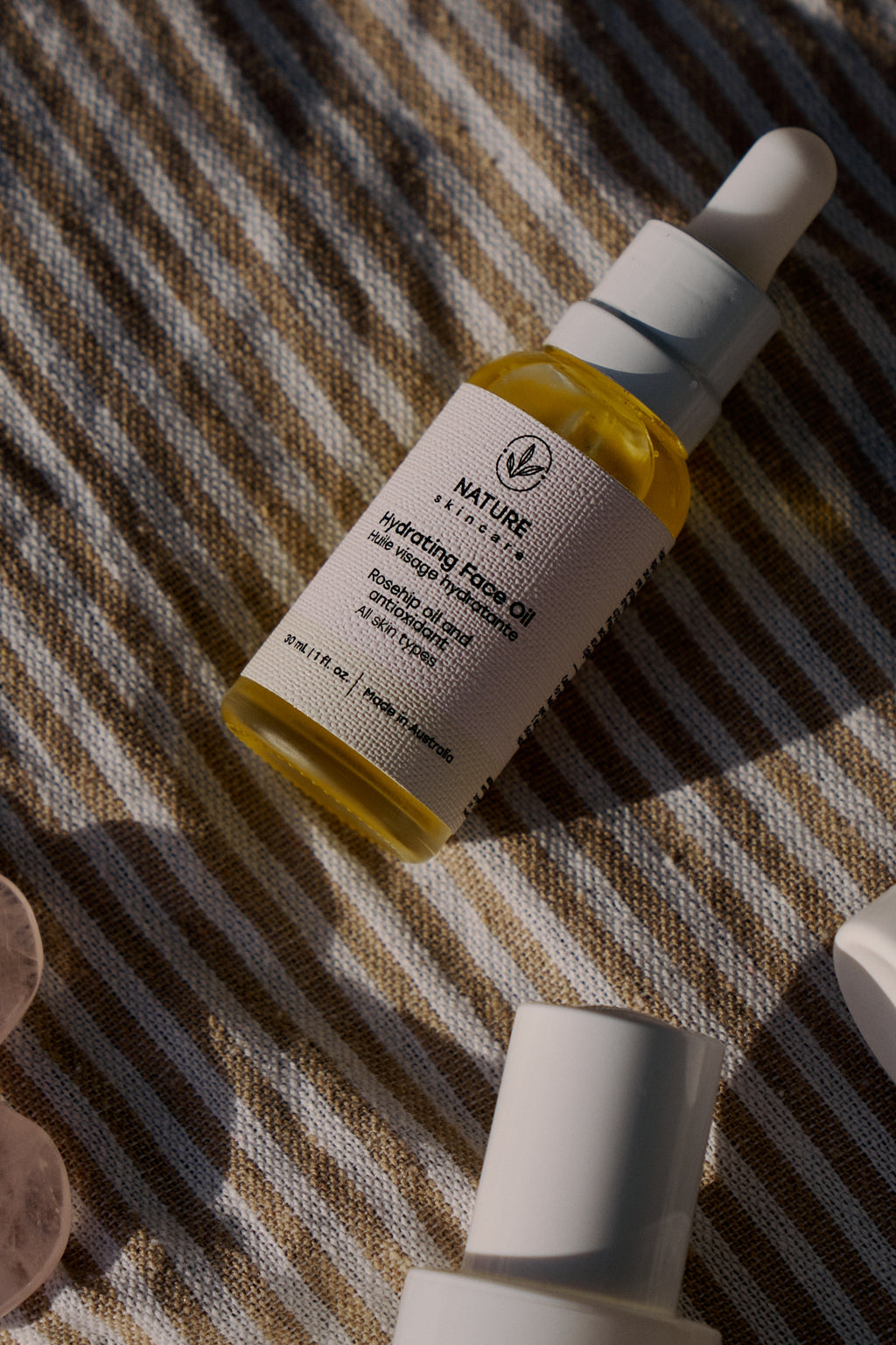 Hydrating face oil bottle flat lay on textured fabric in natural light