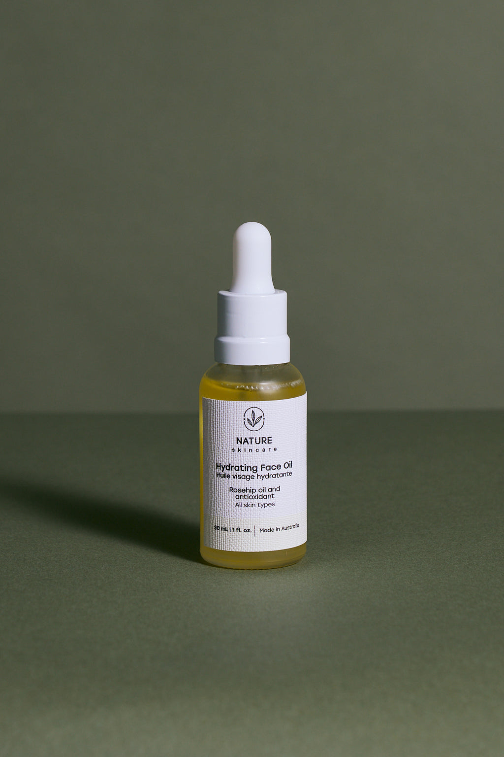 Hydrating face oil dropper bottle on a green background