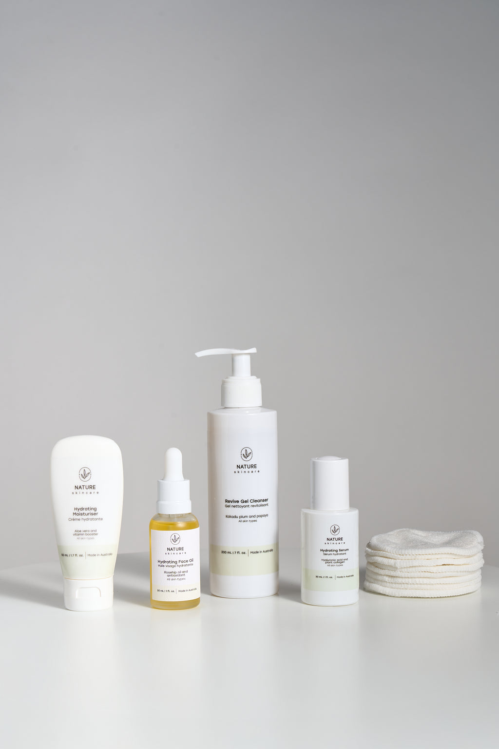 Set of skincare products including bottles and a organic cotton pads on a gray background