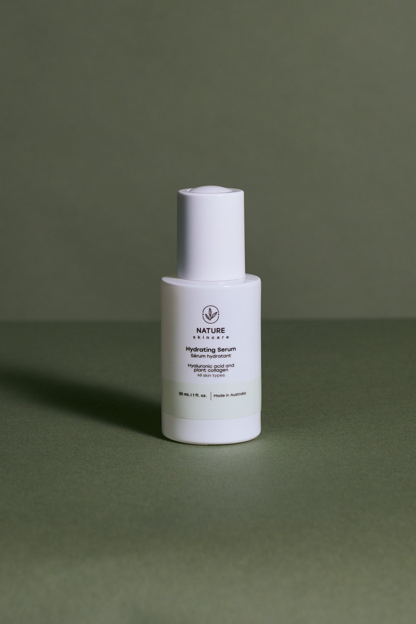 White skincare bottle face serum labeled nature skin care on a green background