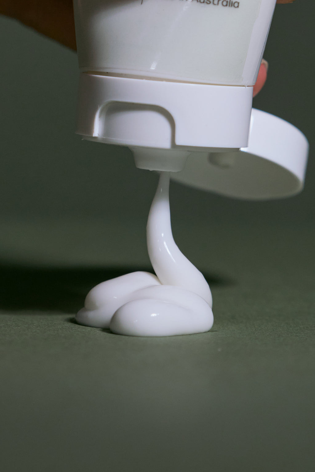 White hydrating moisturiser being dispensed from a pump bottle on a green background